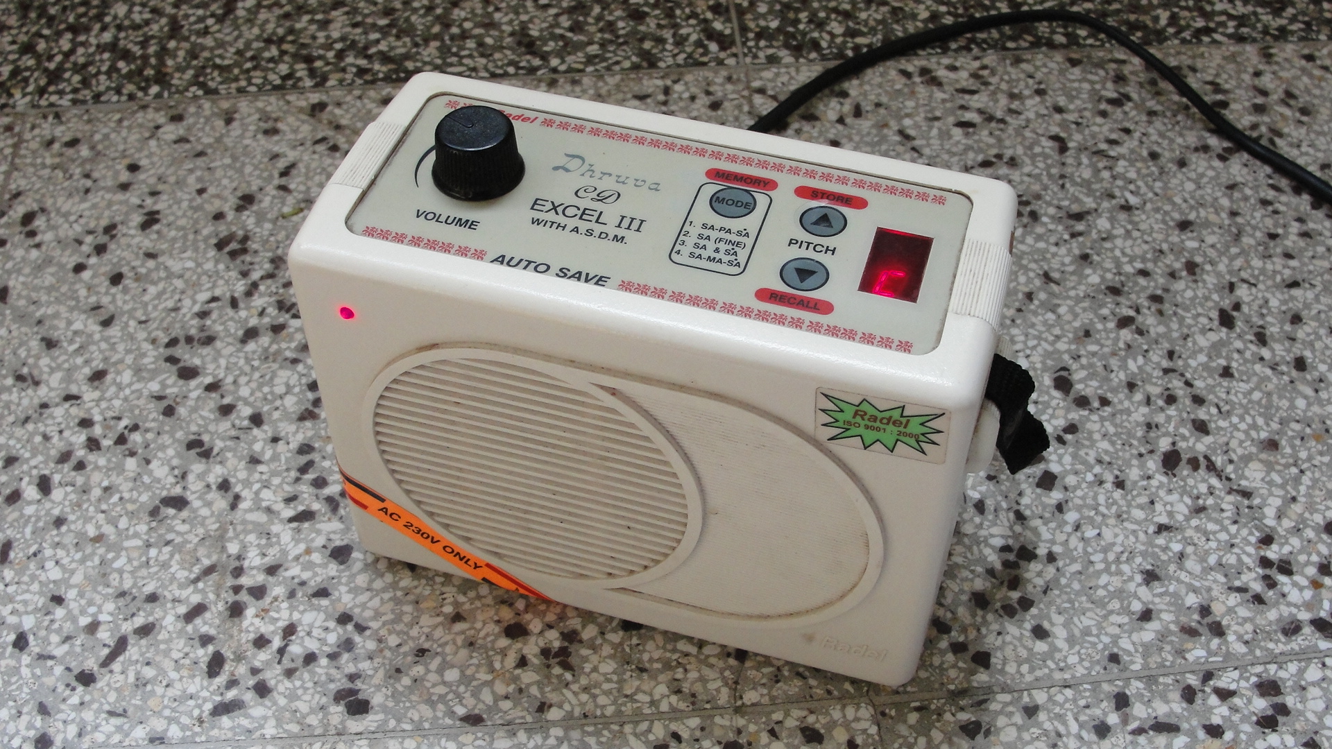 Historical Radel Dhruva Excel III electronic shruti box: a volume knob on the left, pitch buttons near the right, and an illuminated pitch display.